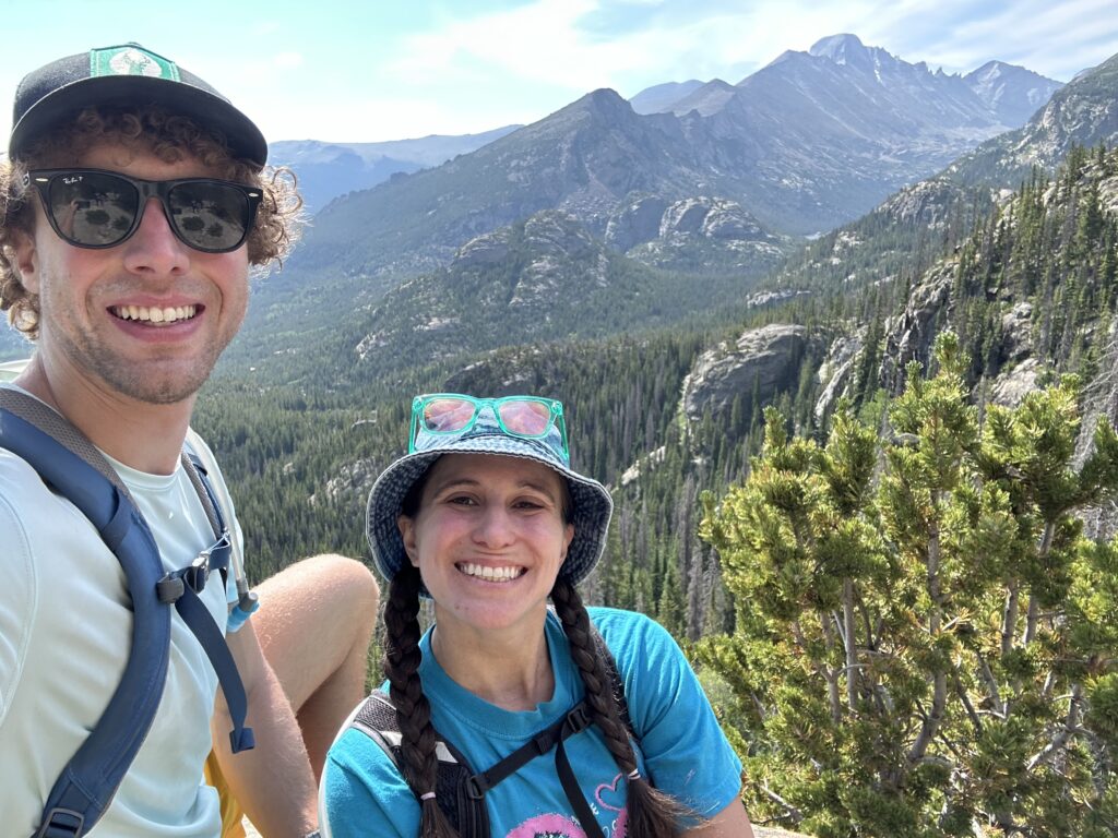 Selfie of Jon and Lai smiling with mountains and trees in the background at RMNP