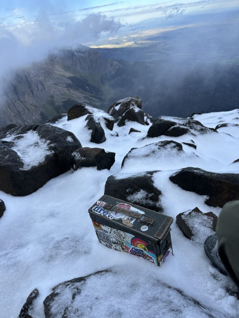 The log box sitting at the snow-capped peak of Mount Sneffels