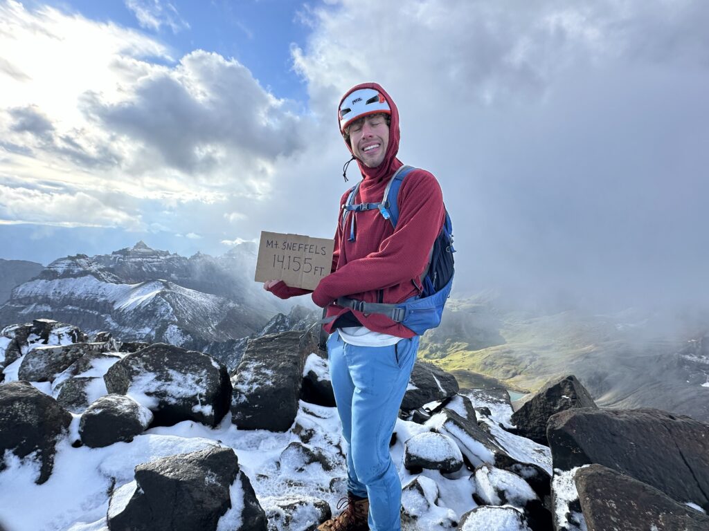 Jon at the summit of Mount Sneffels holding the sign