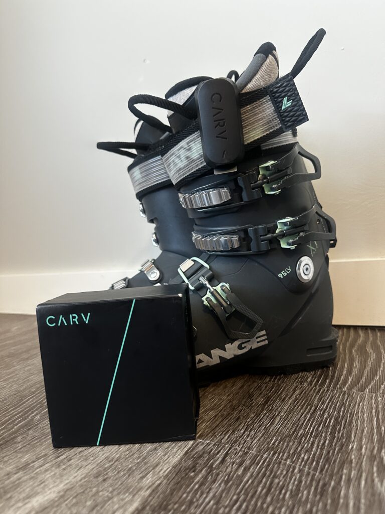 Carv2 ski sensors clipped onto ski boots with Carv box on floor